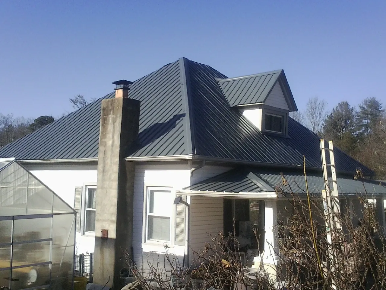 Dark blue standing seam metal roof on a white farmhouse with dormer — Slate & Tile Roof Repair by Roofing Brothers in Loma Mar