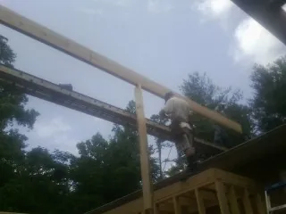 Carpenter setting a ridge beam over a new addition frame — Ice Dam Removal by Roofing Brothers in Loma Mar