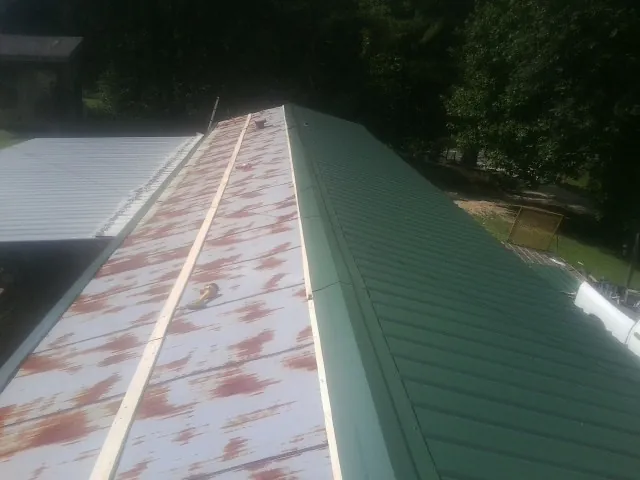 Old rusted panels beside newly installed green metal roofing — Wind Damage Roof Repair by Roofing Brothers in Loma Mar