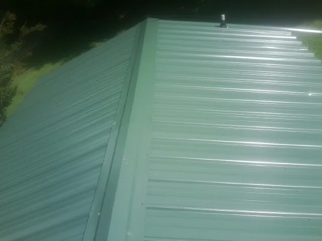 New green metal panels meeting at the ridge of a roof — Flat Roof Repair work by our crew in Loma Mar