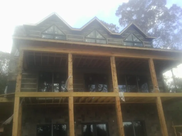 Dormers and porch framing on a large log home under construction — Roof Coating work by our crew in Loma Mar