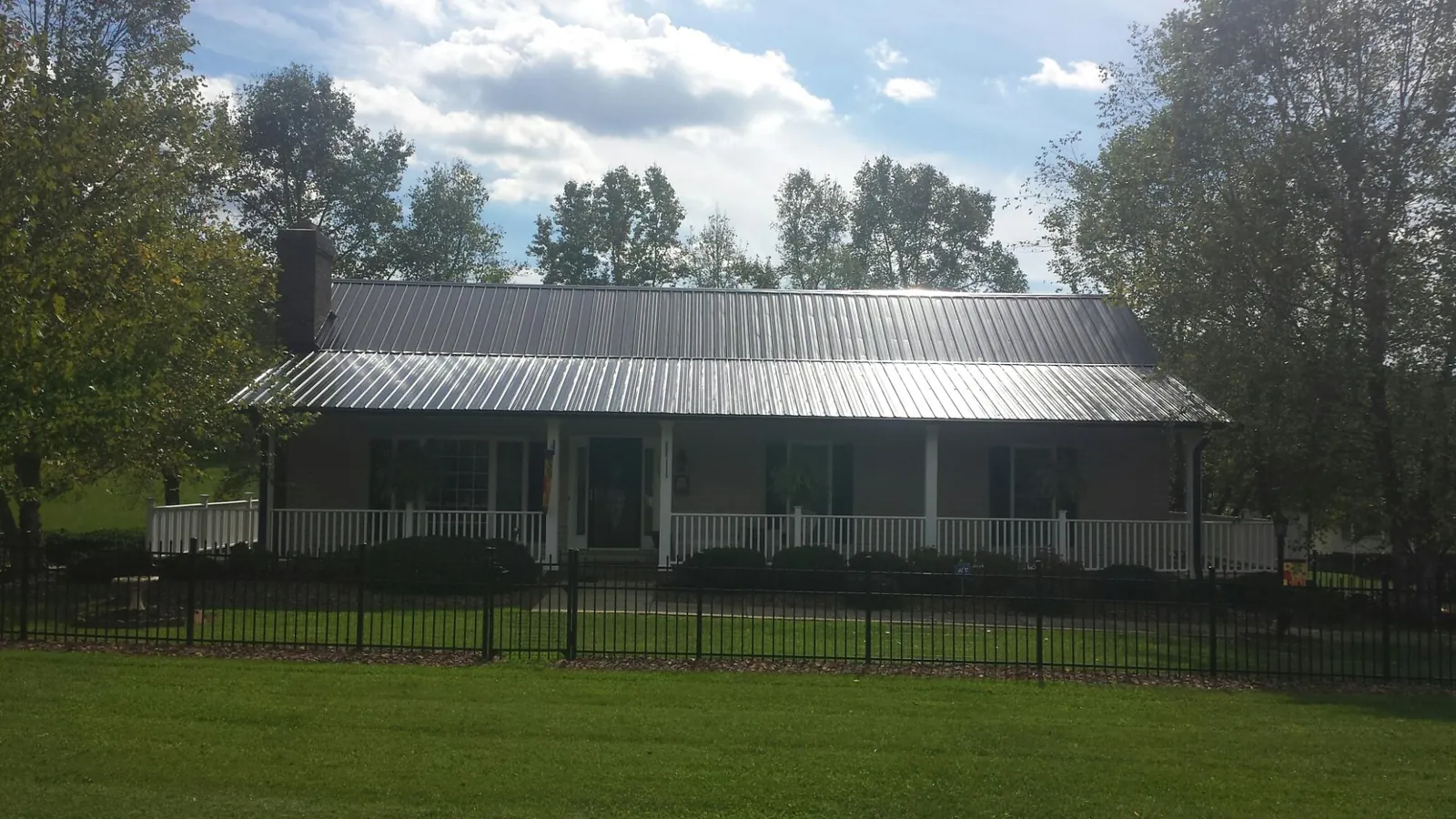 Gray metal roof on a brick ranch with a full width front porch — Gutter Guard Installation work by our crew in Loma Mar