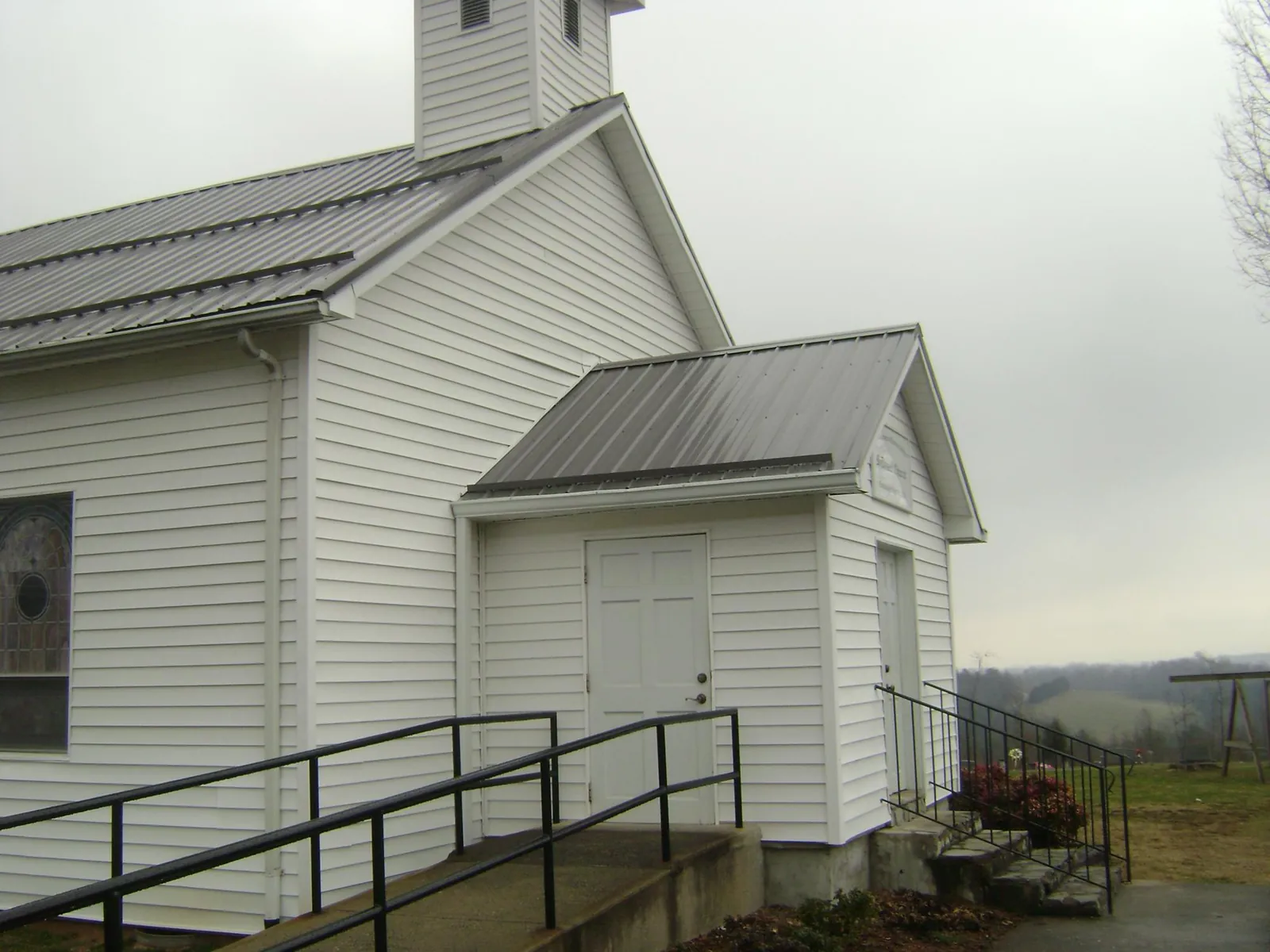 Gray metal roof on a white clapboard church with a steeple in Loma Mar
