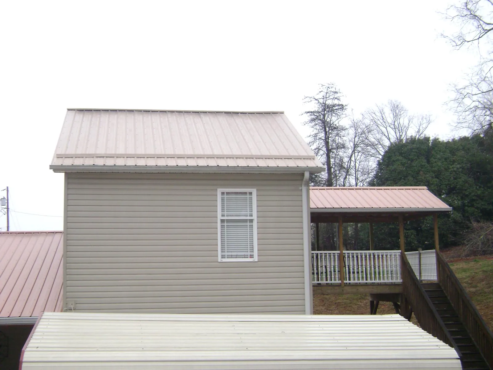 Tan metal roofs on a two story addition and attached porch, from a Roof Replacement job in Loma Mar