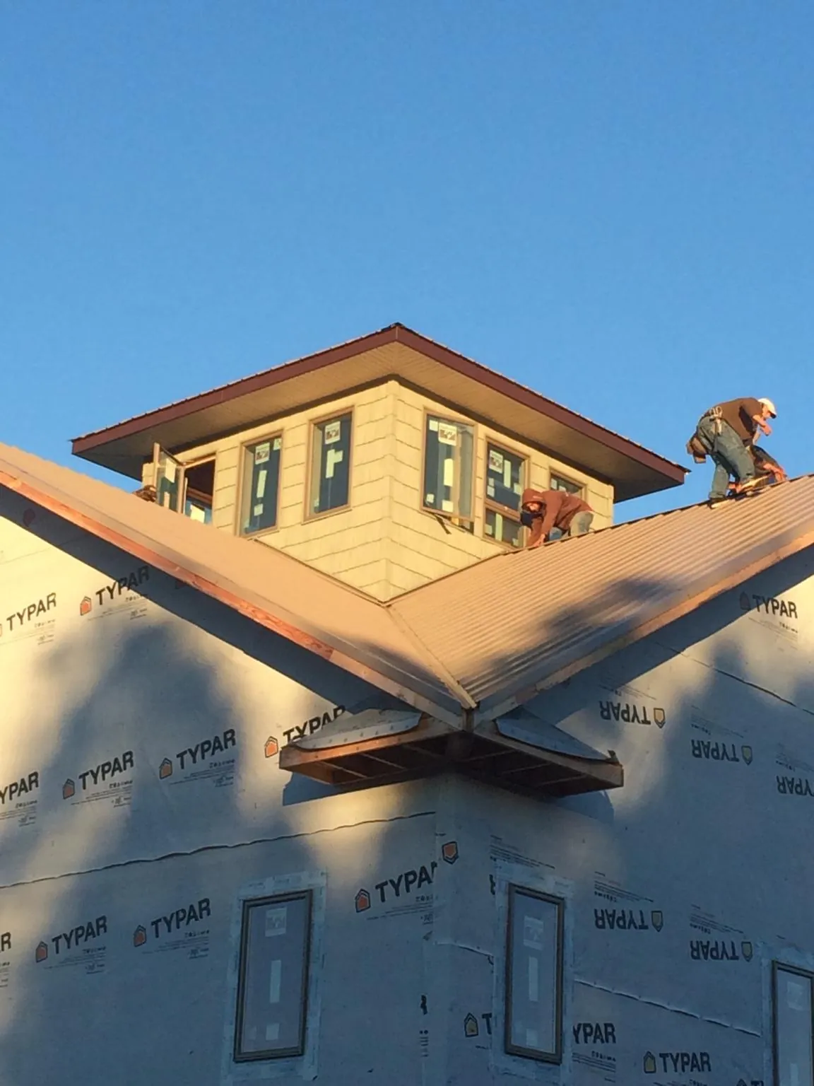 Roofers working around a rooftop cupola on a new metal roof at sunset — Roof Waterproofing in Loma Mar by Roofing Brothers